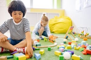 Child Minding Certification - Kids enjoying playtime with toys and blocks in a bright kindergarten classroom.