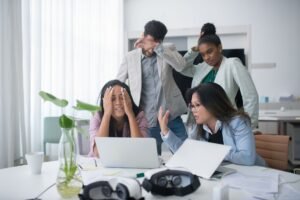Problem Solving Certification - A diverse group of coworkers appearing stressed while working in a modern office meeting room.