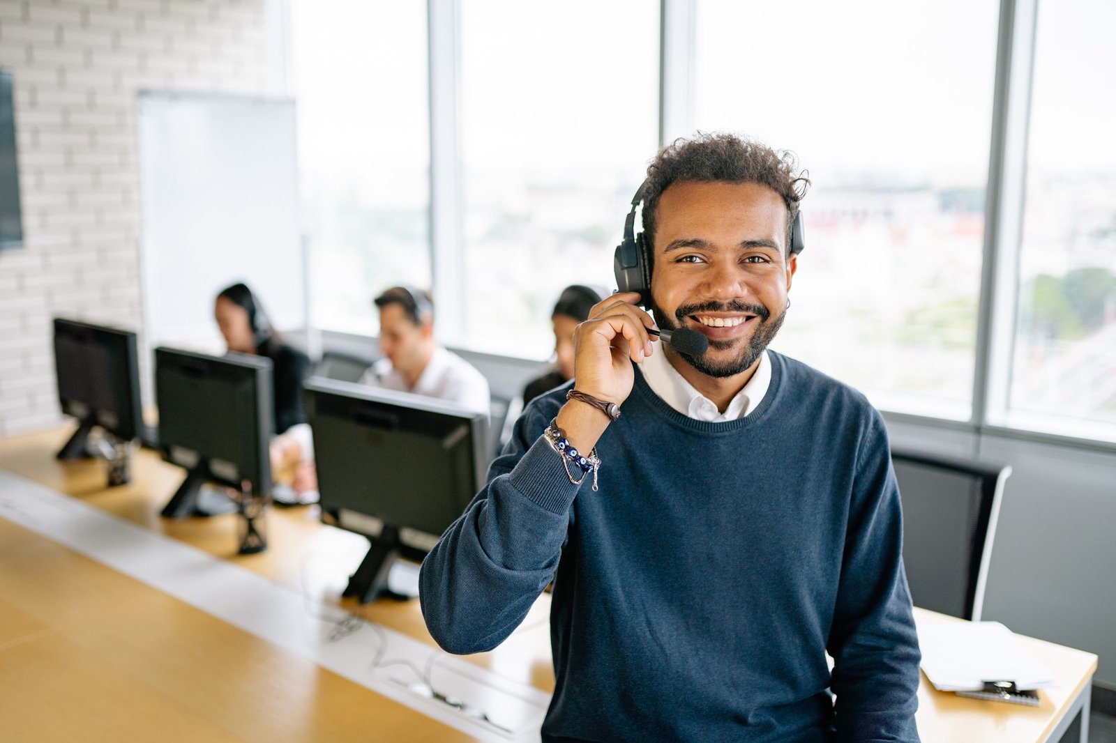 Achieving Sales on the Telephone Certification - Cheerful male call center agent with headset in a bright office environment.