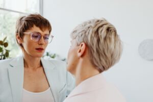 Tackling Sensitive Workplace Conversations Certification - Lesbian couple engaged in a thoughtful indoor conversation, capturing emotion and connection.