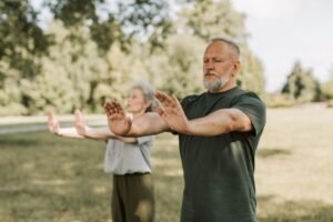 The Benefits of Tai Chi Certification - Elderly couple engaged in outdoor Tai Chi, promoting wellness and fitness in a park setting.