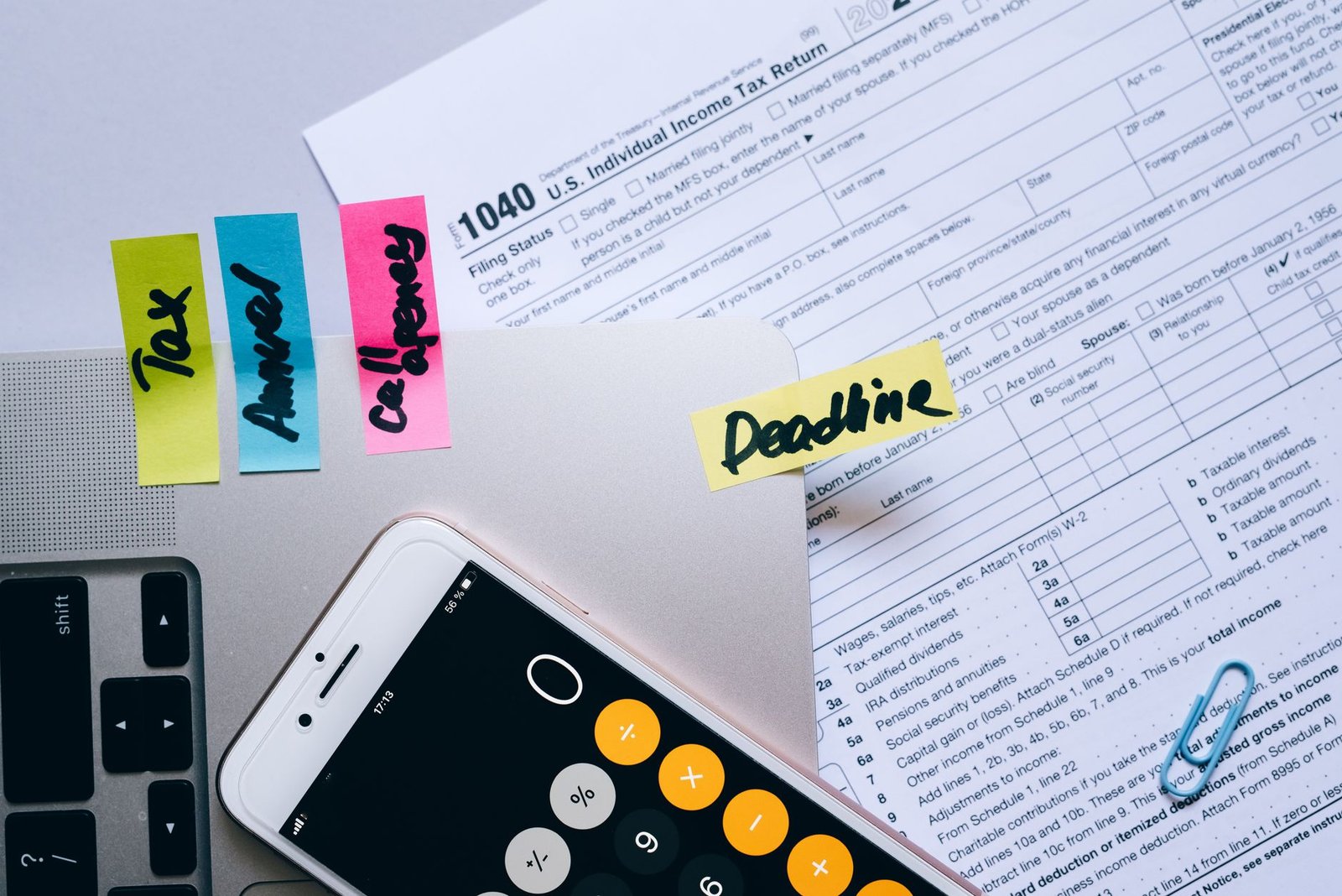 Payroll – How to Calculate Net and Gross Pay Certification - Office desk flat lay showing tax documents, calculator app on smartphone, sticky notes, and paperclips.