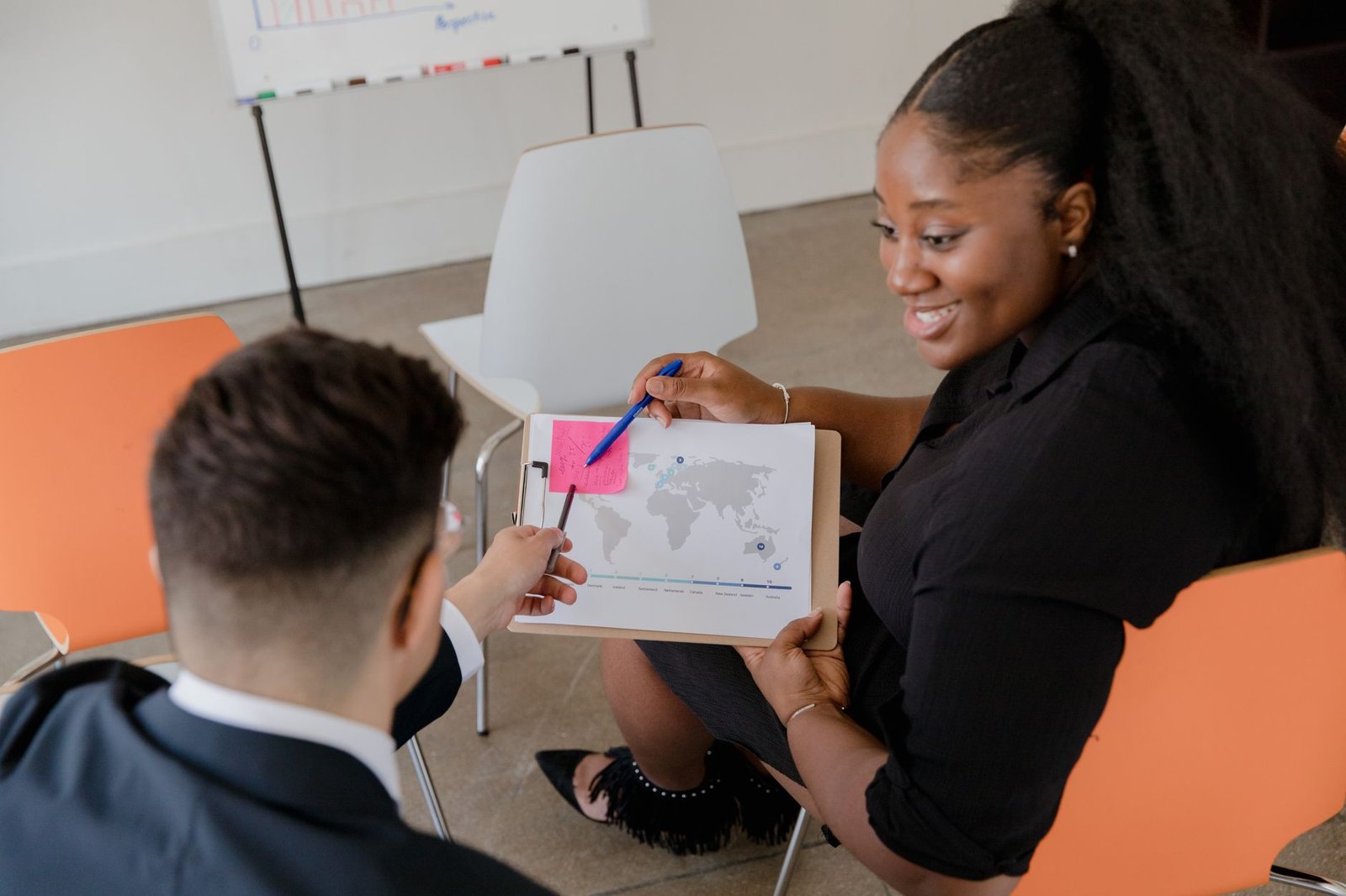 Career Planning Certification - Two colleagues discussing a world map in an office setting, promoting teamwork and planning.