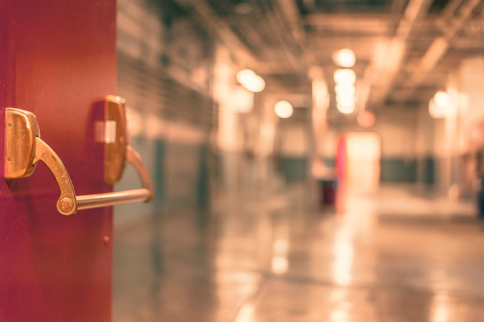 Positive Handling in Schools Certification - Abstract image of a blurred industrial corridor with focus on a red door handle.